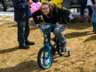 teenage girl on small bike with training wheels