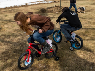 teenage girls riding on small bikes with training wheels