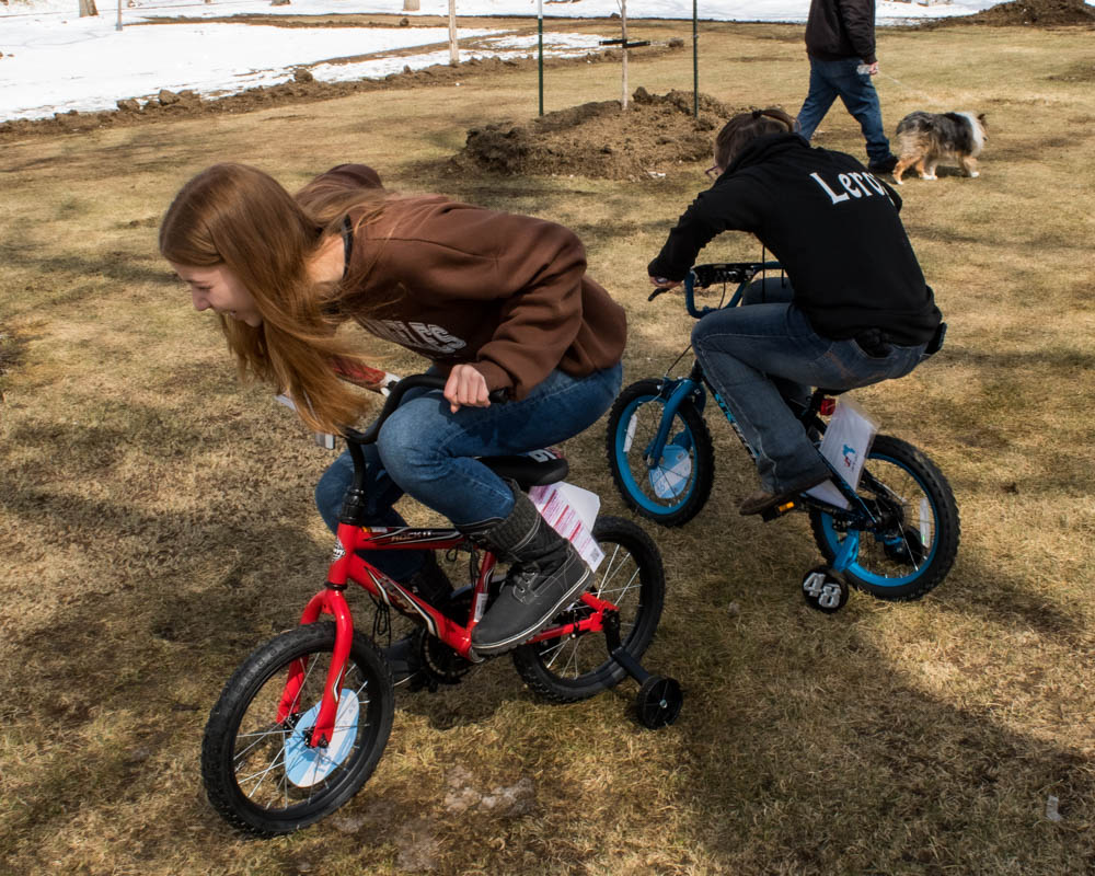 teenage girls riding on small bikes with training wheels