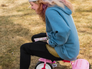 Teenage girl on tiny tricycle