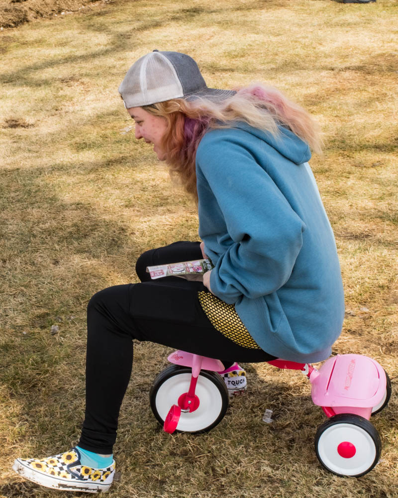 Teenage girl on tiny tricycle